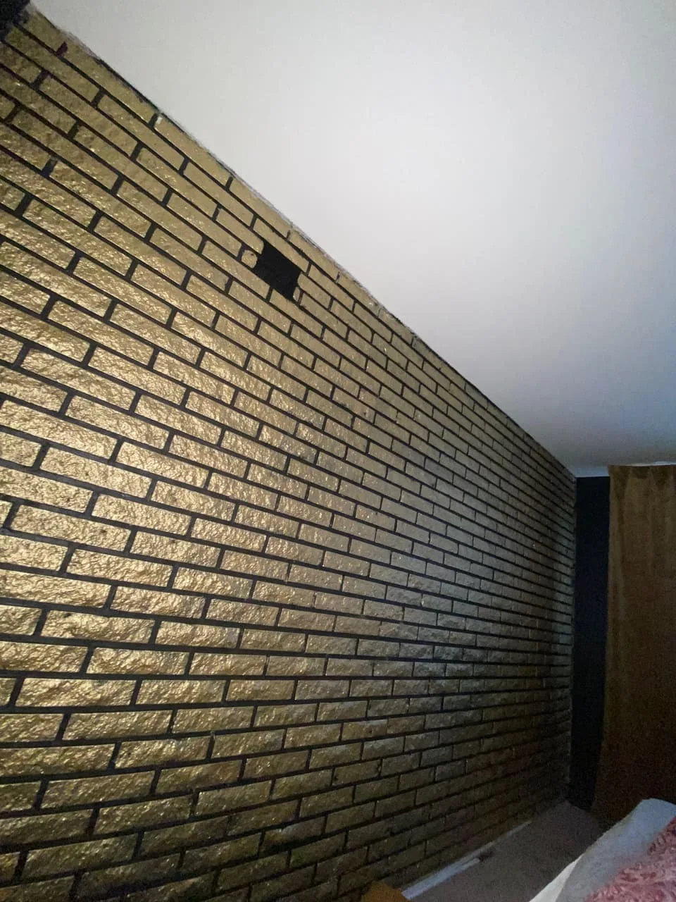 Ferdig mursteinsvegg malt sort med gullfinish – detalj etter omarbeiding